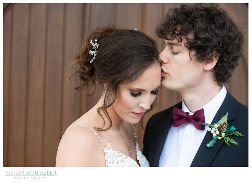 groom kissing bride's head